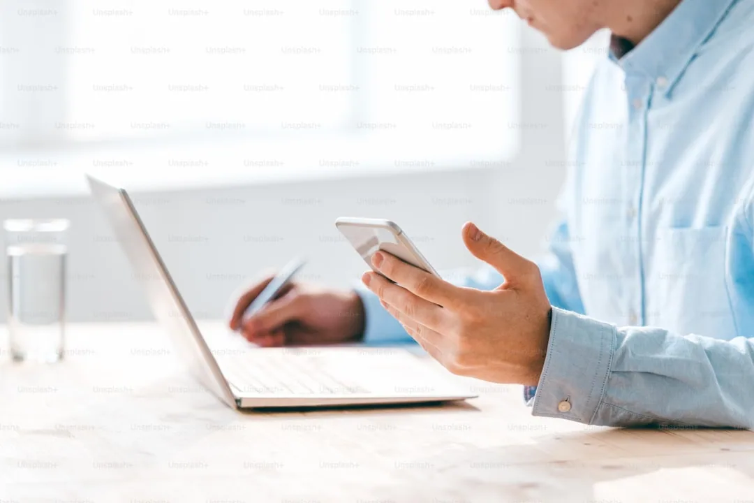 Osoba porównująca oferty telefoniczne na laptopie i smartfonie